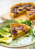 Assiette présentant une part de tarte aux lentilles corail avec des oignons rouges