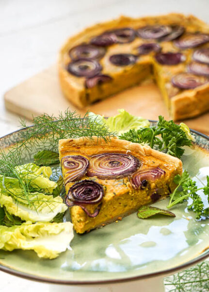 Assiette présentant une part de tarte aux lentilles corail avec des oignons rouges